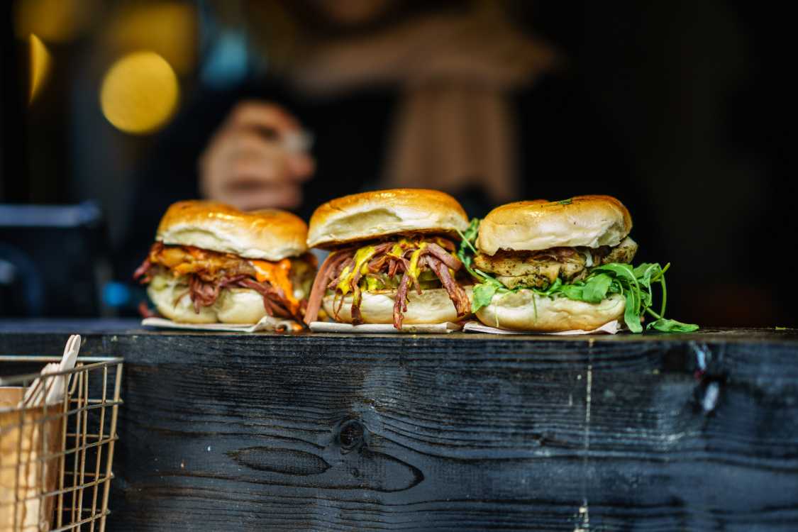 Three barbecue sandwiches on a wooden table.