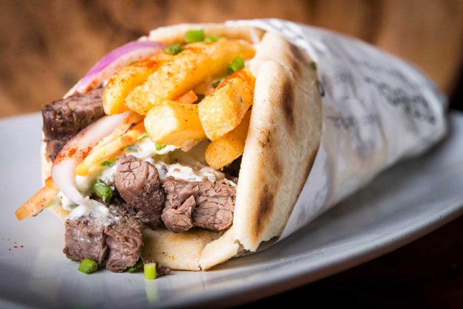 Close up of a gyro with fries.