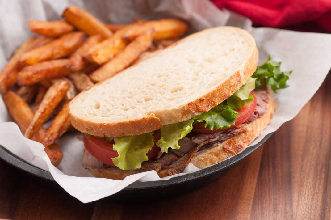 A plate for French fries and a roast beef sandwich.