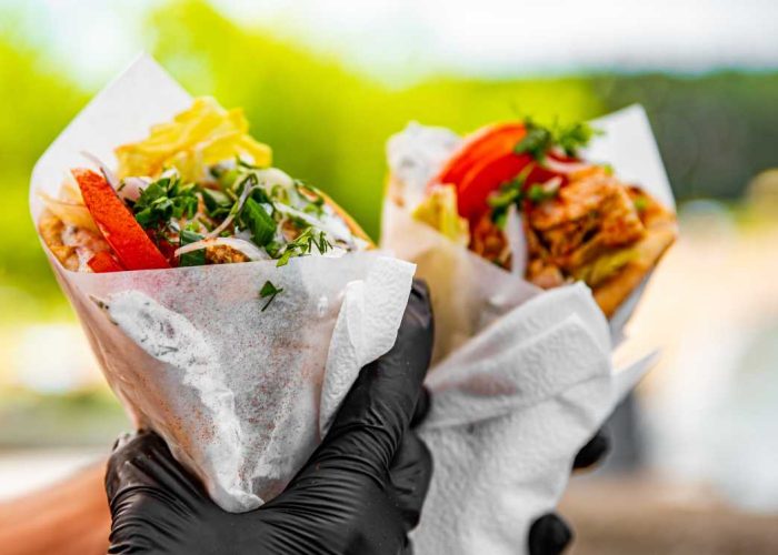 A close up of hands holding two gyro sandwiches.